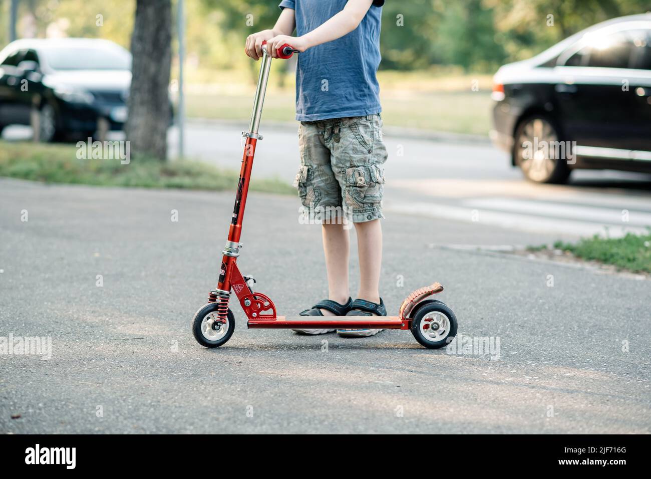 Young boy rides a scooter on the road in summer Stock Photo Alamy