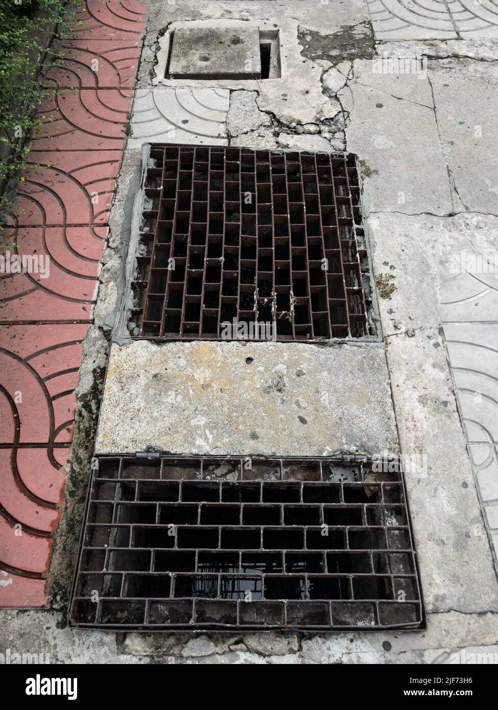The metal manhole cover on the sidewalk near the street in the city, front view with the copy space. Stock Photo