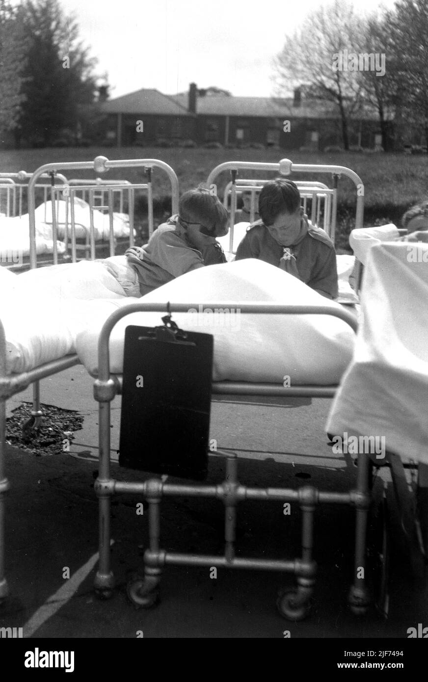 1942, historical, wartime and two cub scouts sitting in metal hospital beds outside The Queen Mary's Hospital for Children at Carshalton, London, England, UK. Built in 1908 as the Southern Hospital, it became a children's infirmary in 1909 and renamed after a visit by Queen Mary in 1915. It was the most heavily bombed hospital in the greater London area, with the first attack in 1940. The new threats posed by the VI and V2 rockets, saw total evacuation take place in July 1944 with children taken to other locations in England and Wales. Stock Photo