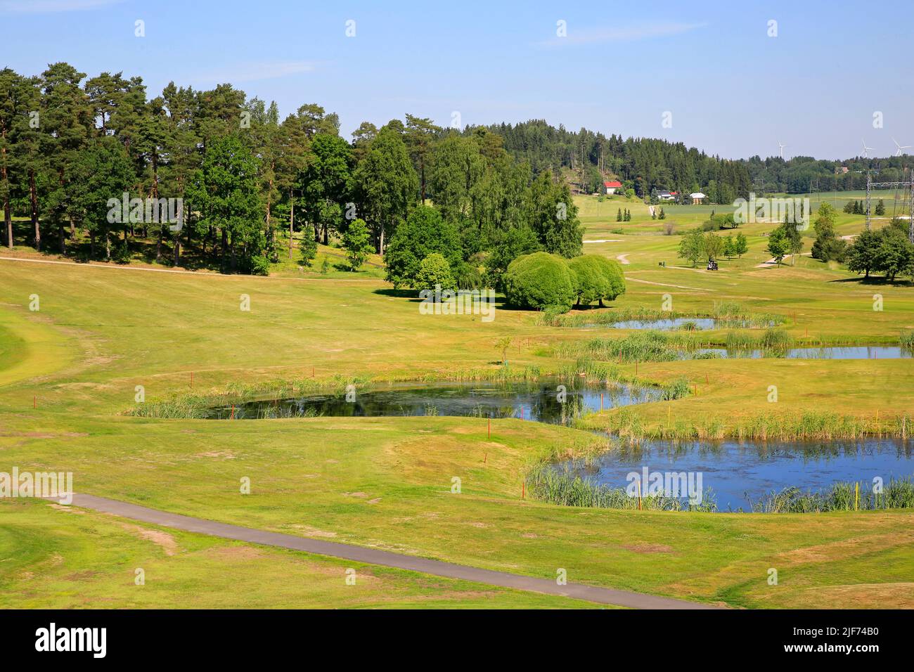 View to an idyllic golf course on a beautiful day of summer with small ponds and forest. Stock Photo