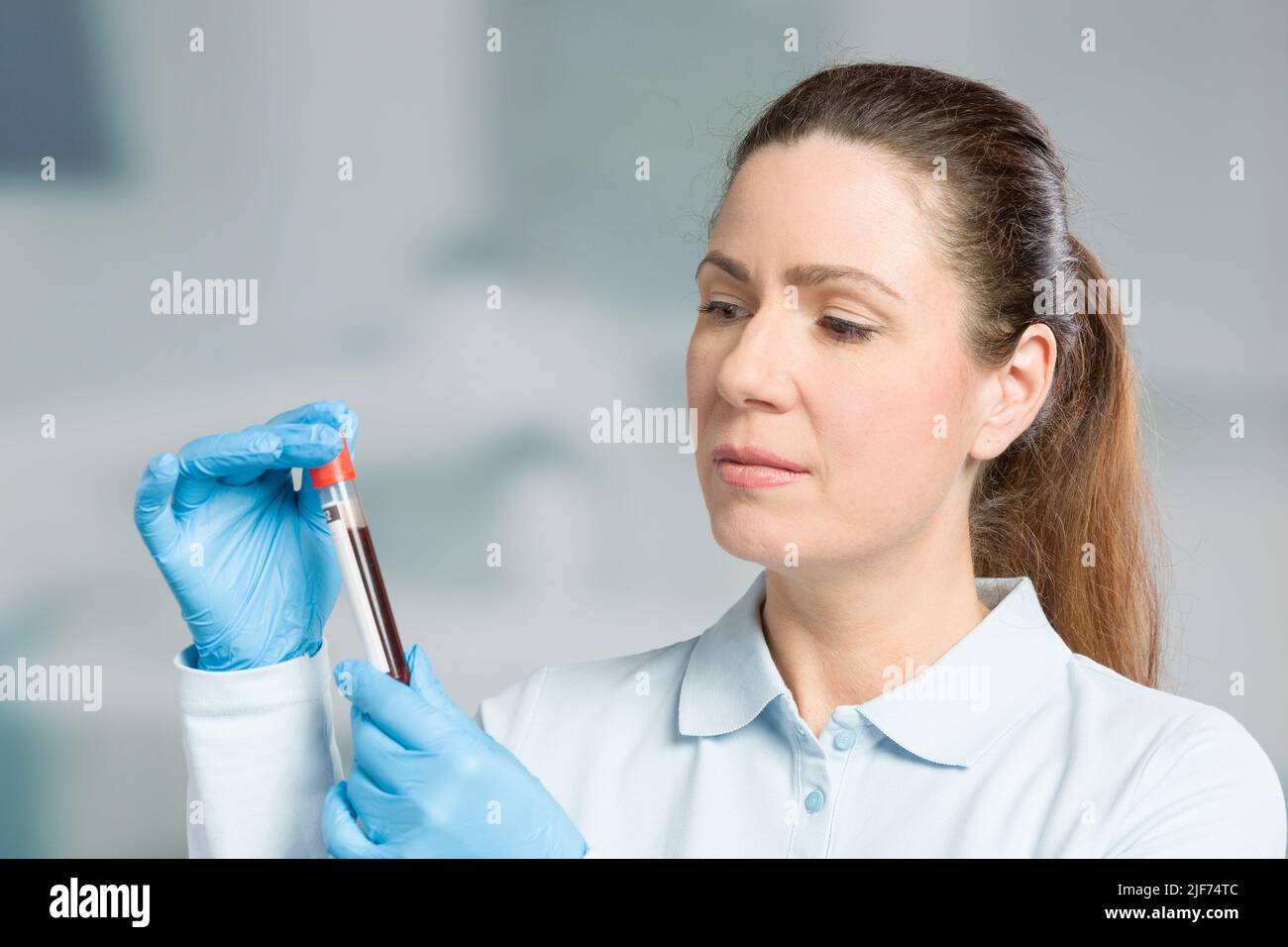 nurse or female scientist is handling a blood sample in a test tube in