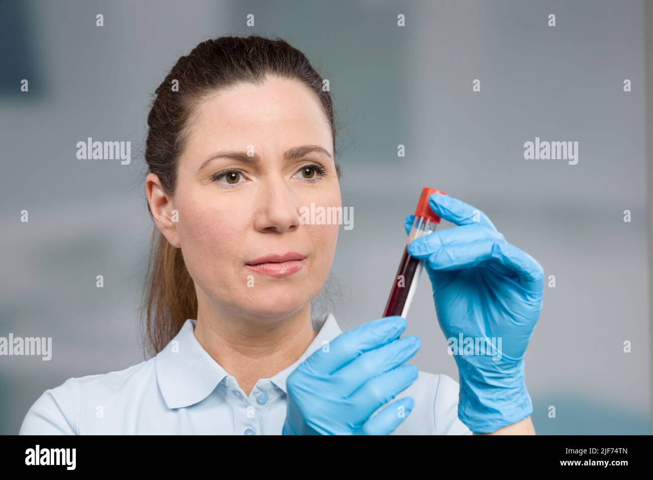 nurse or female scientist is handling a blood sample in a test tube in
