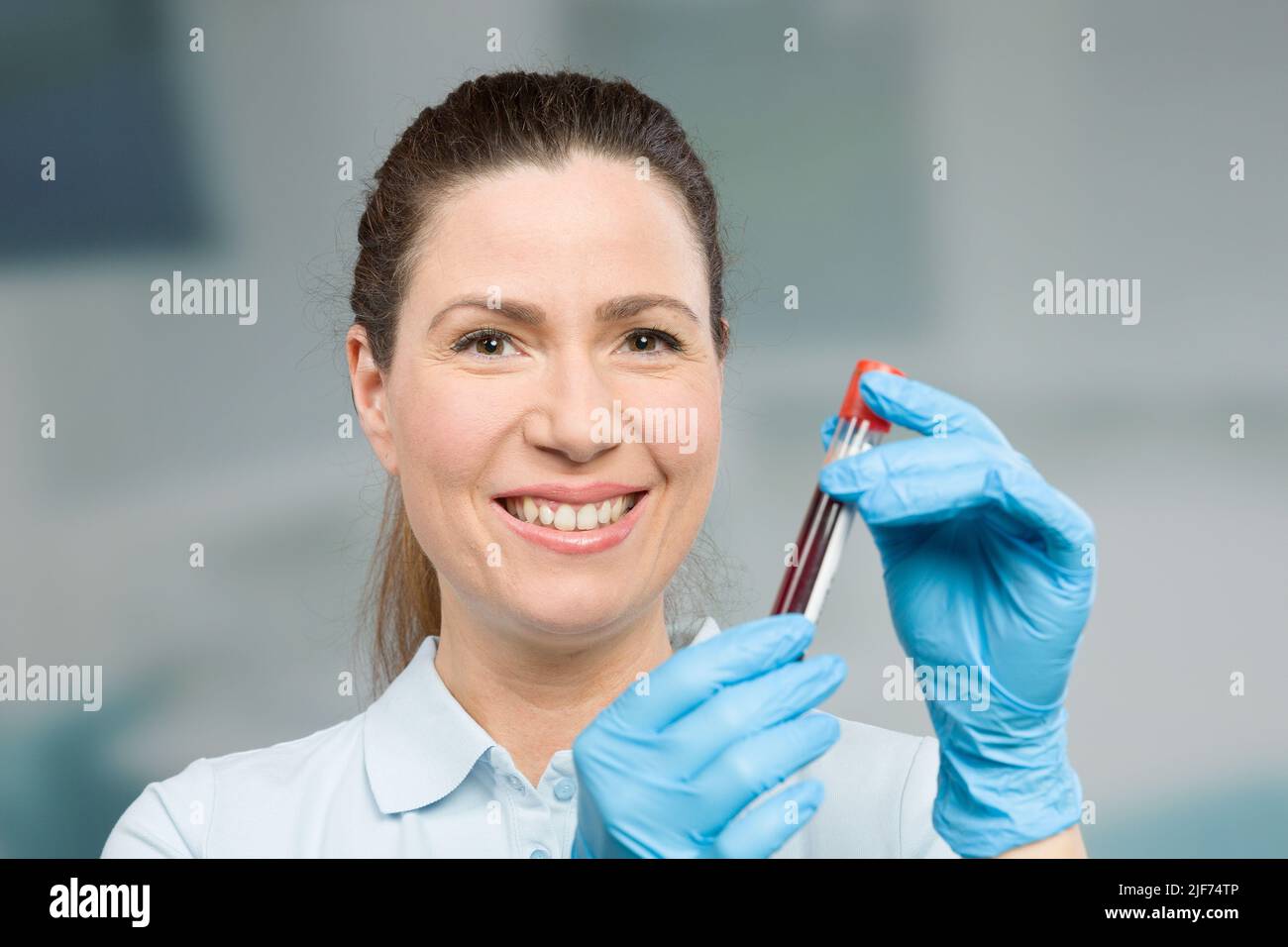 nurse or female scientist is handling a blood sample in a test tube in
