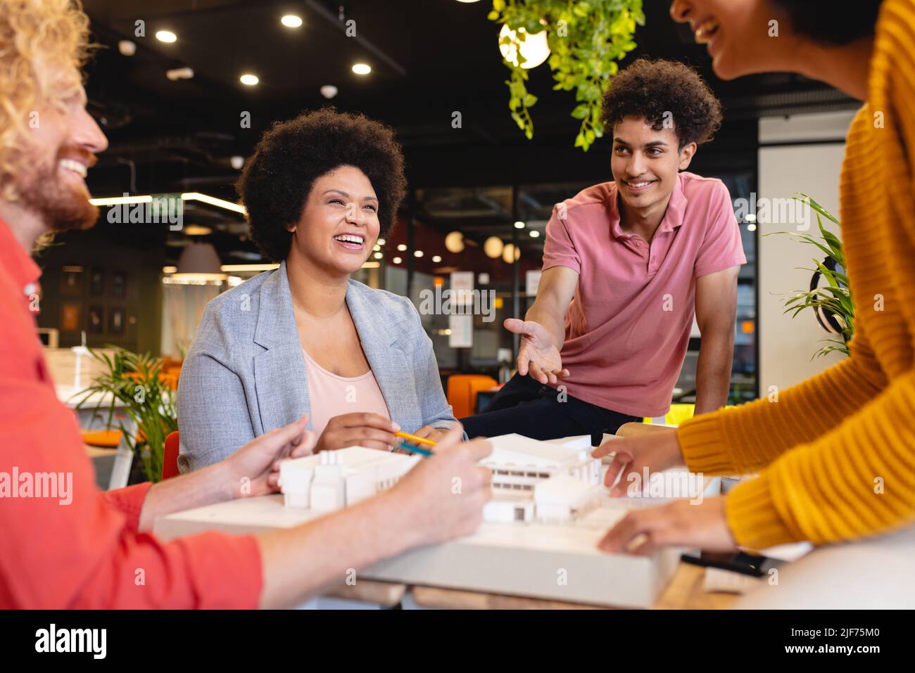 Smiling multiracial male and female architects discussing over ...