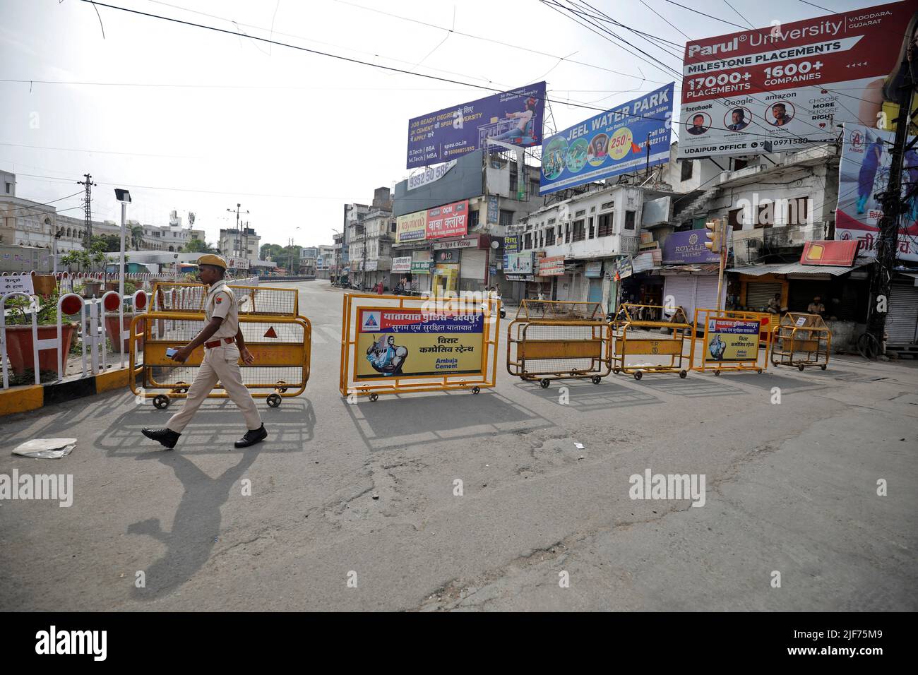A police officer walks past barriers on a street during restrictions imposed by authorities after the death of Kanhaiyalal Teli, a Hindu tailor, who was killed by two suspected Muslims after they videoed themselves slaying him, in Udaipur in the northwestern state of Rajasthan, India, June 30, 2022. REUTERS/Amit Dave Stock Photo