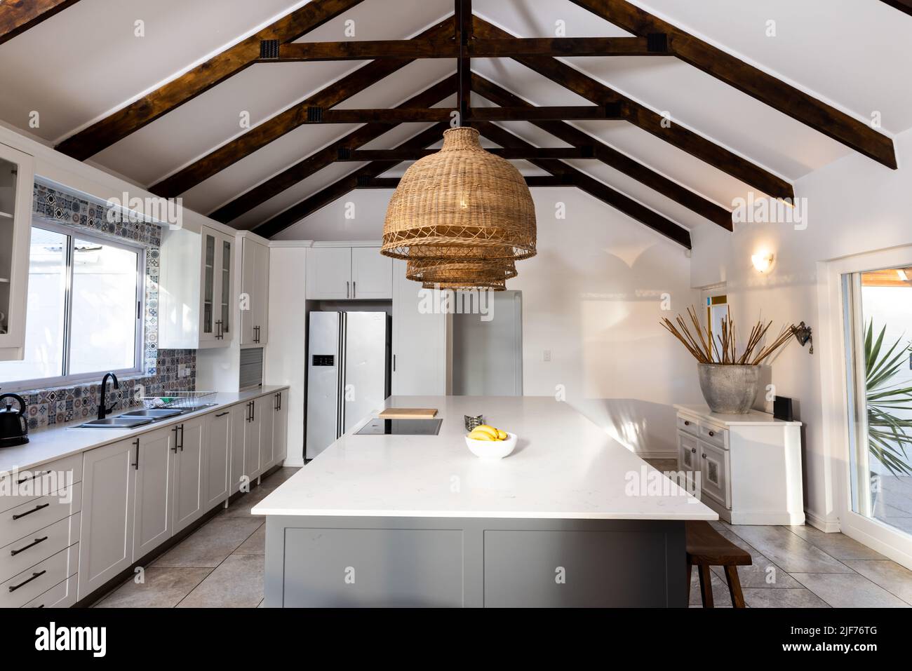 Lighting equipment hanging in a row from mansard roof over kitchen island in modern kitchen Stock Photo