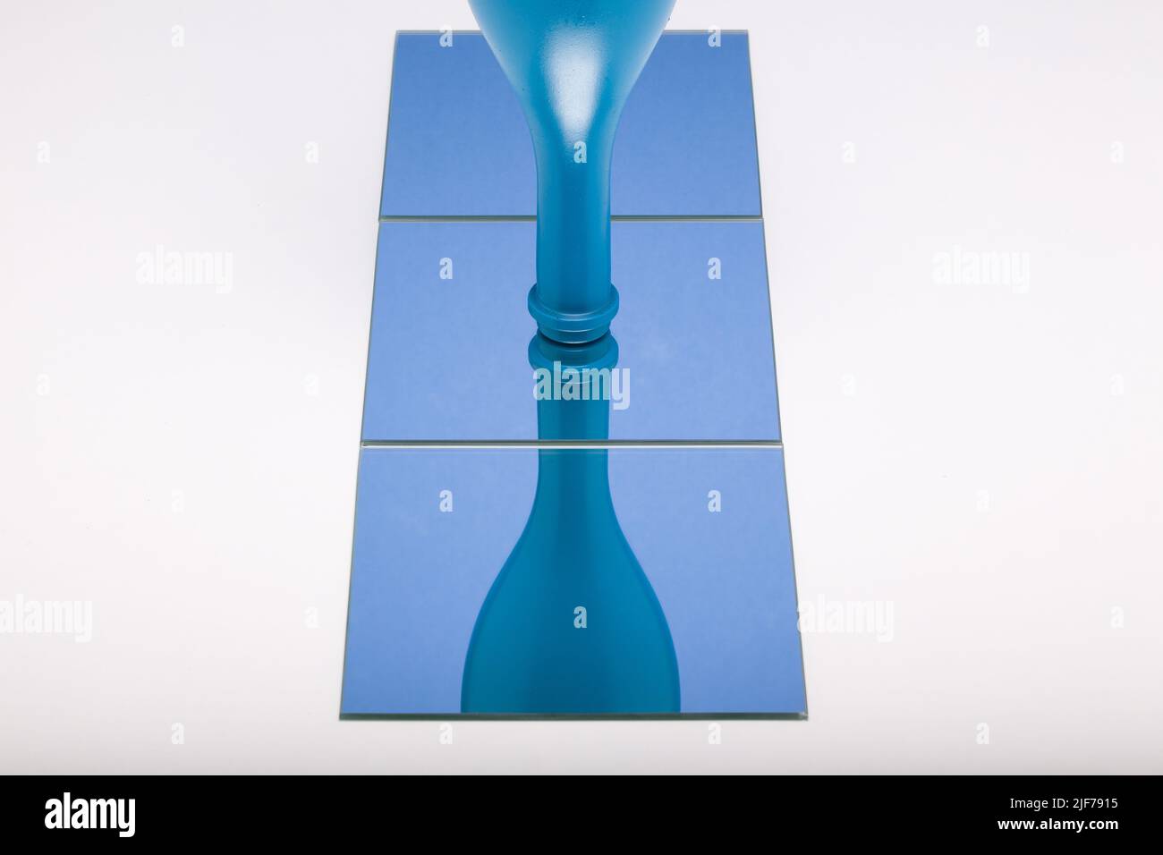 Horizontal image of mirror with reflection blue bottle in blue mirror. Concept of wine products. Stock Photo
