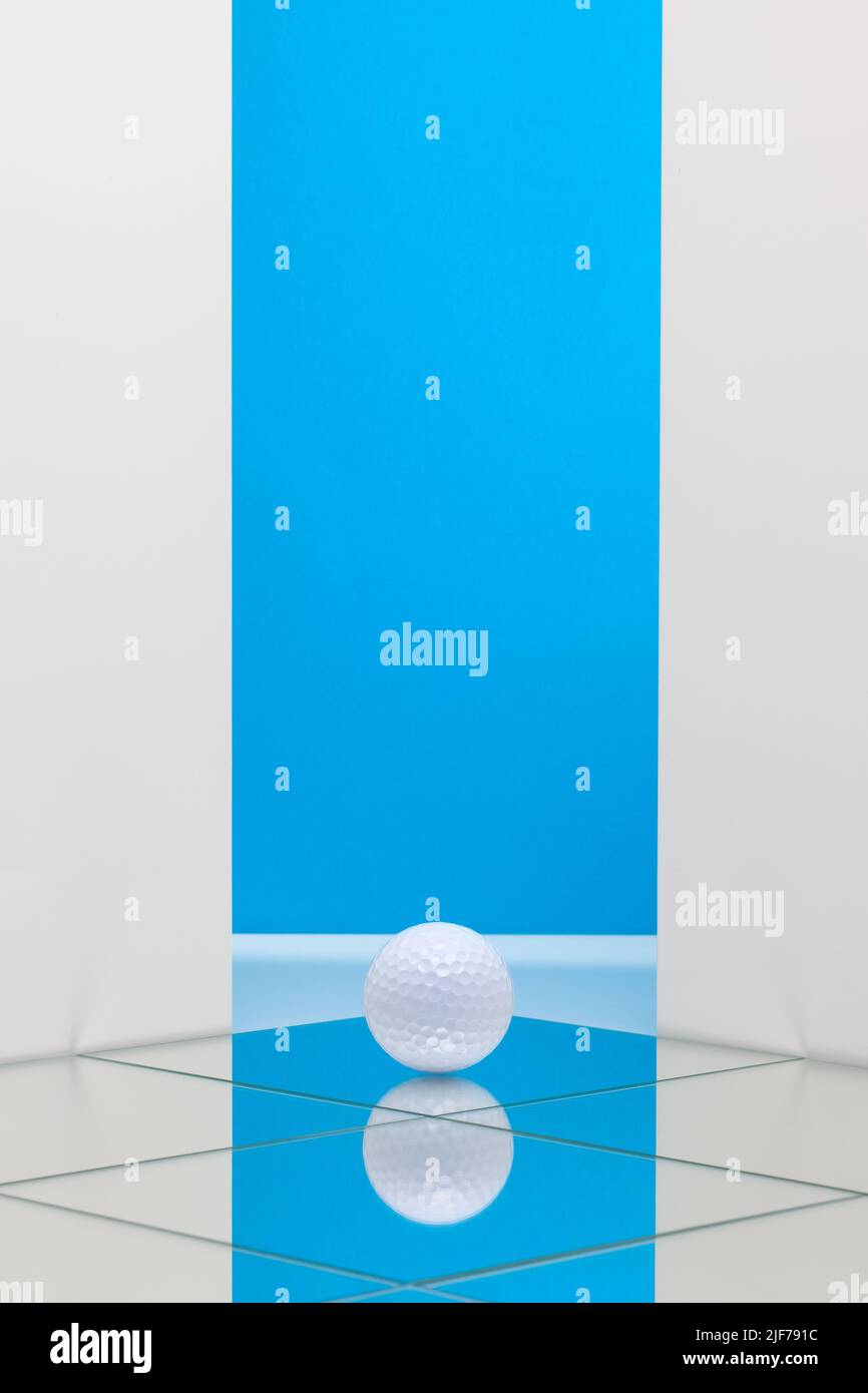 White golf ball on the floor from mirrors. White golf ball on blue background.  Sport Concept and Idea Stock Photo