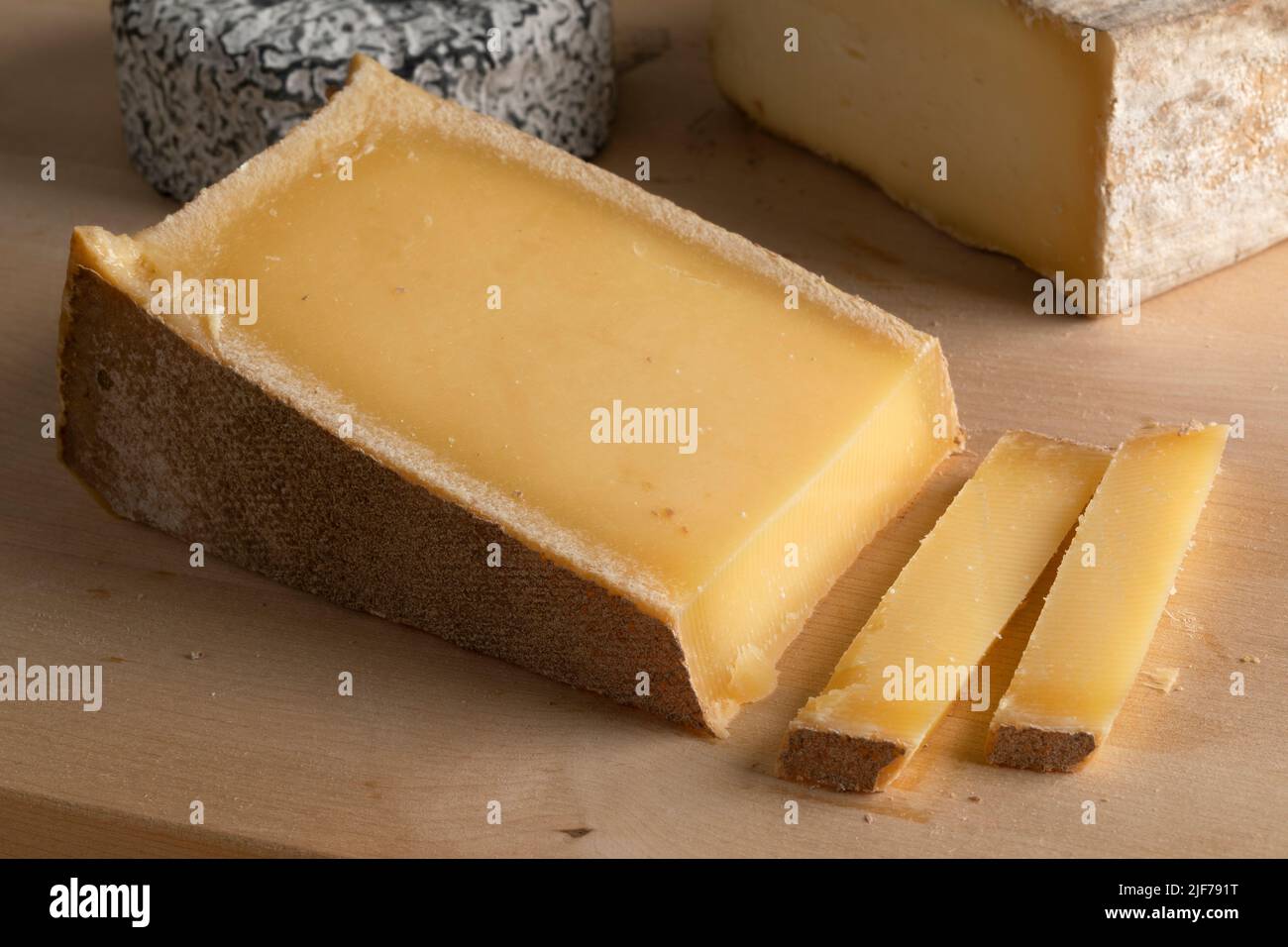 Piece of  French Abondance cheese and slices on a cutting board close up Stock Photo