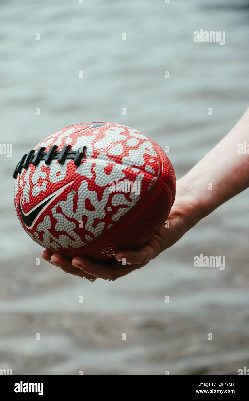 A vertical closeup of the hand holding a Nike rugby ball Stock Photo - Alamy