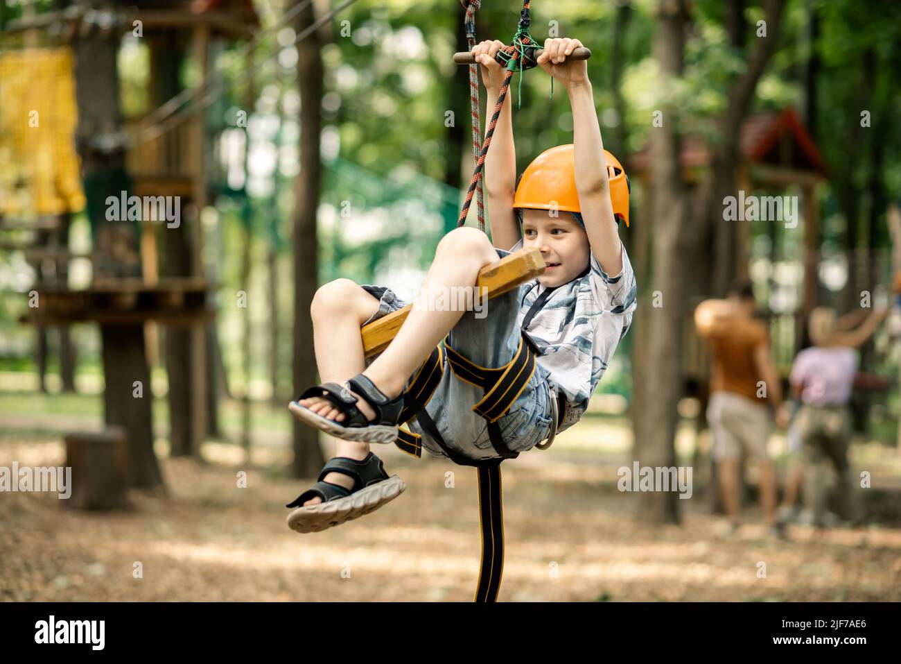 A young boy is hanging on the line in the rope park. Sports ...