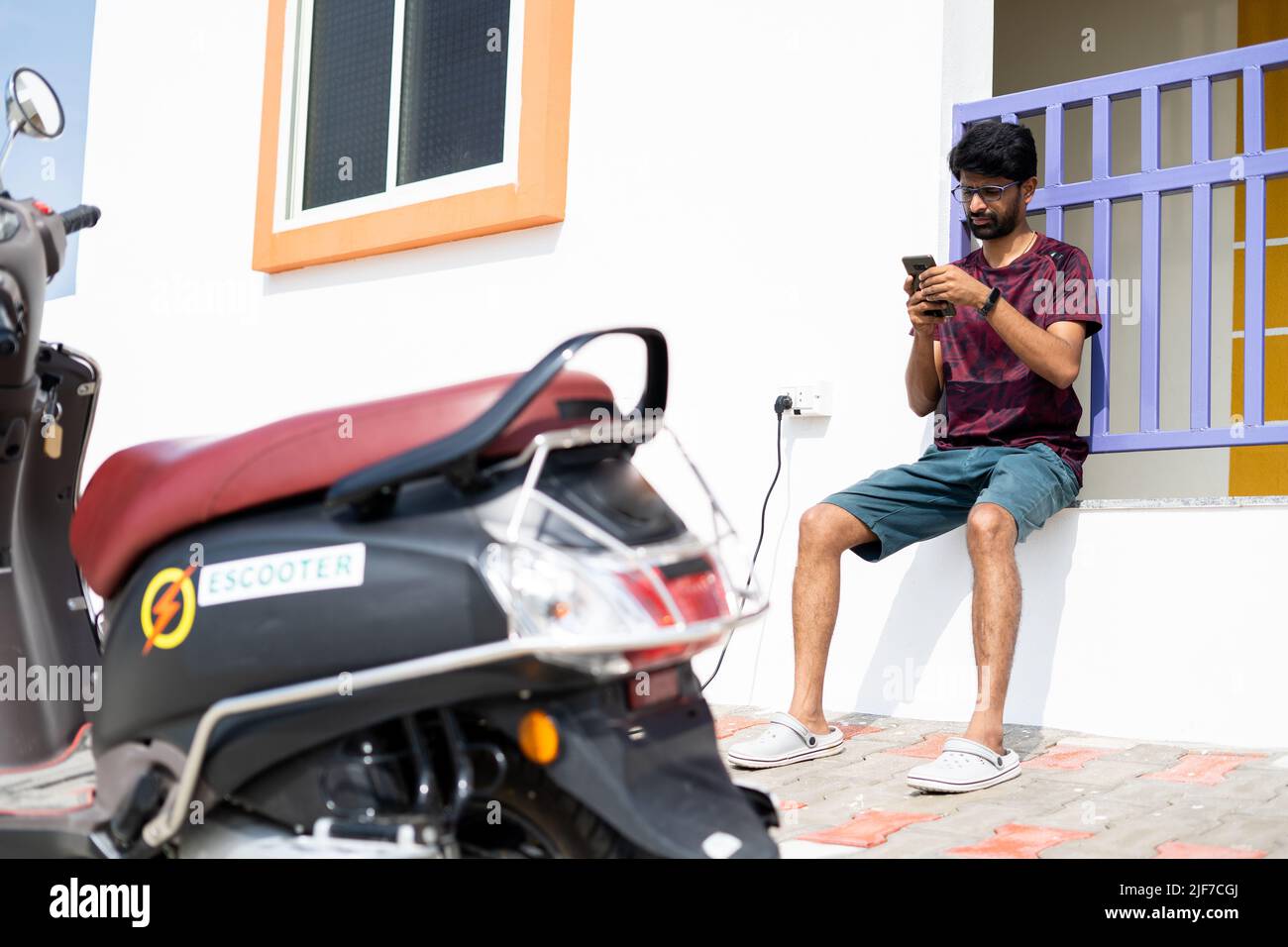 Young man using mobile phone near charging point during recharging of