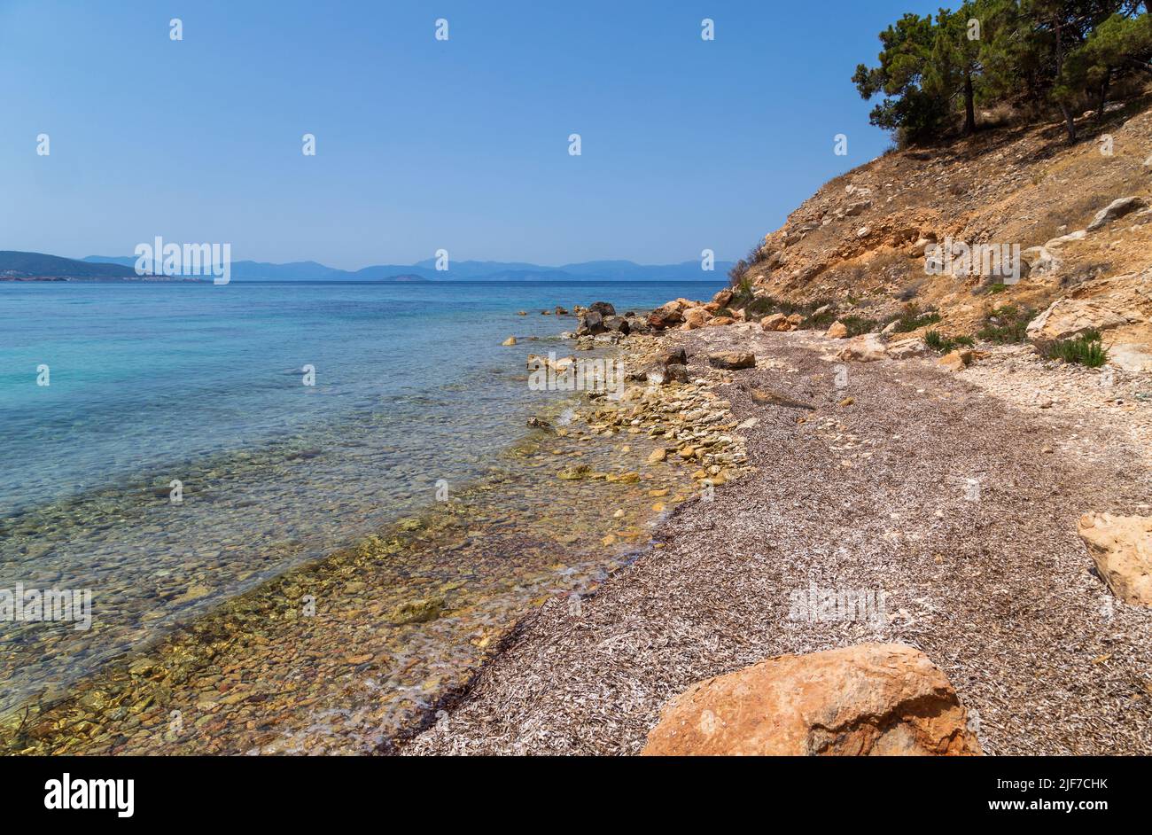 The wild coast of Aegina island with clear and blue waters of Mediterranean sea in the Saronic gulf, Greece. Stock Photo