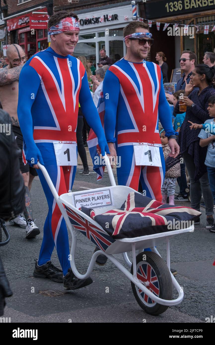 Two men of Pinner Players Theatre Company push a wheel barrow down