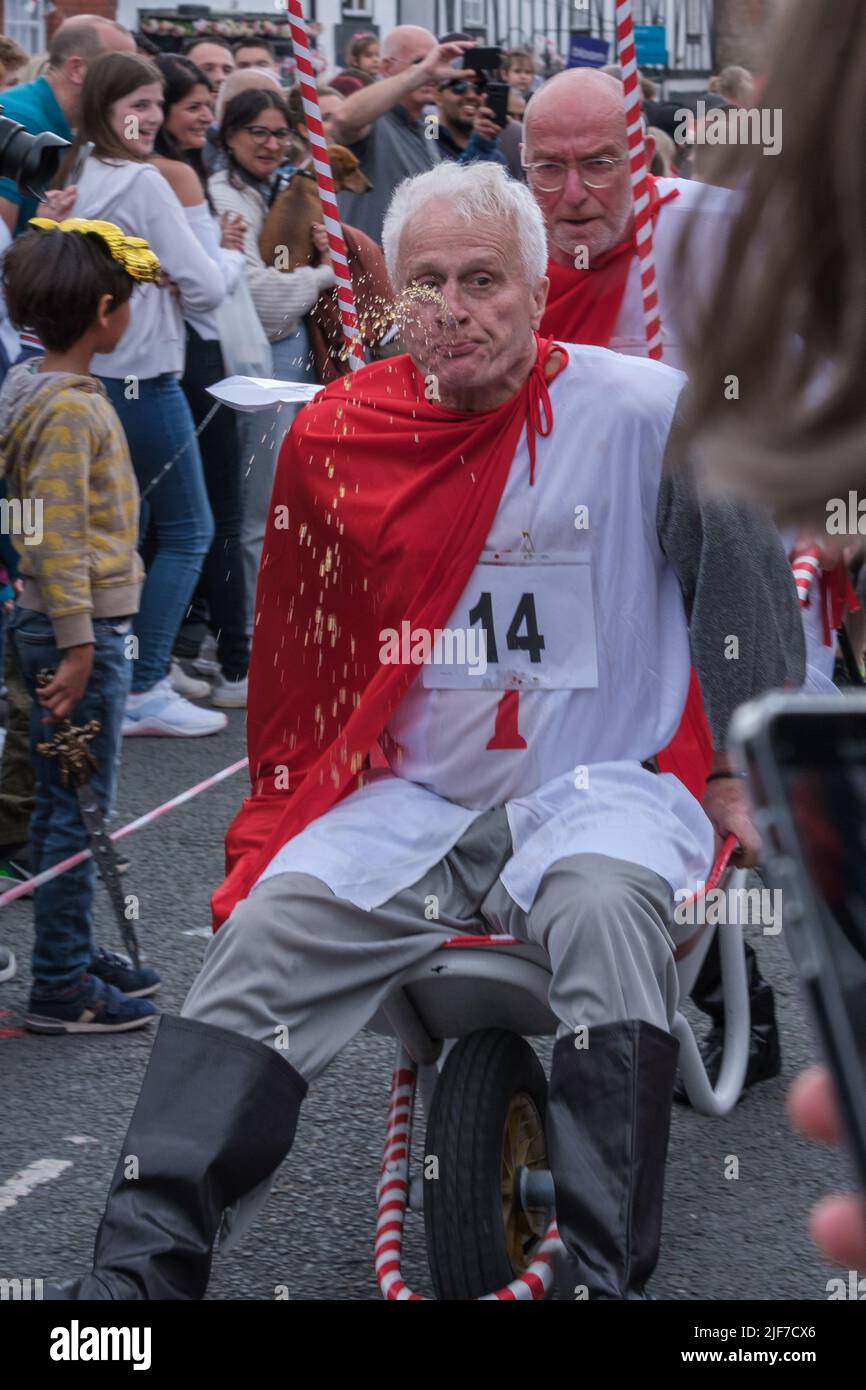 One of the men of the Norfolk and Chance team, voted best dressed, spits out beer during the wheelbarrow race, St. George’s Day Celebration. London. Stock Photo
