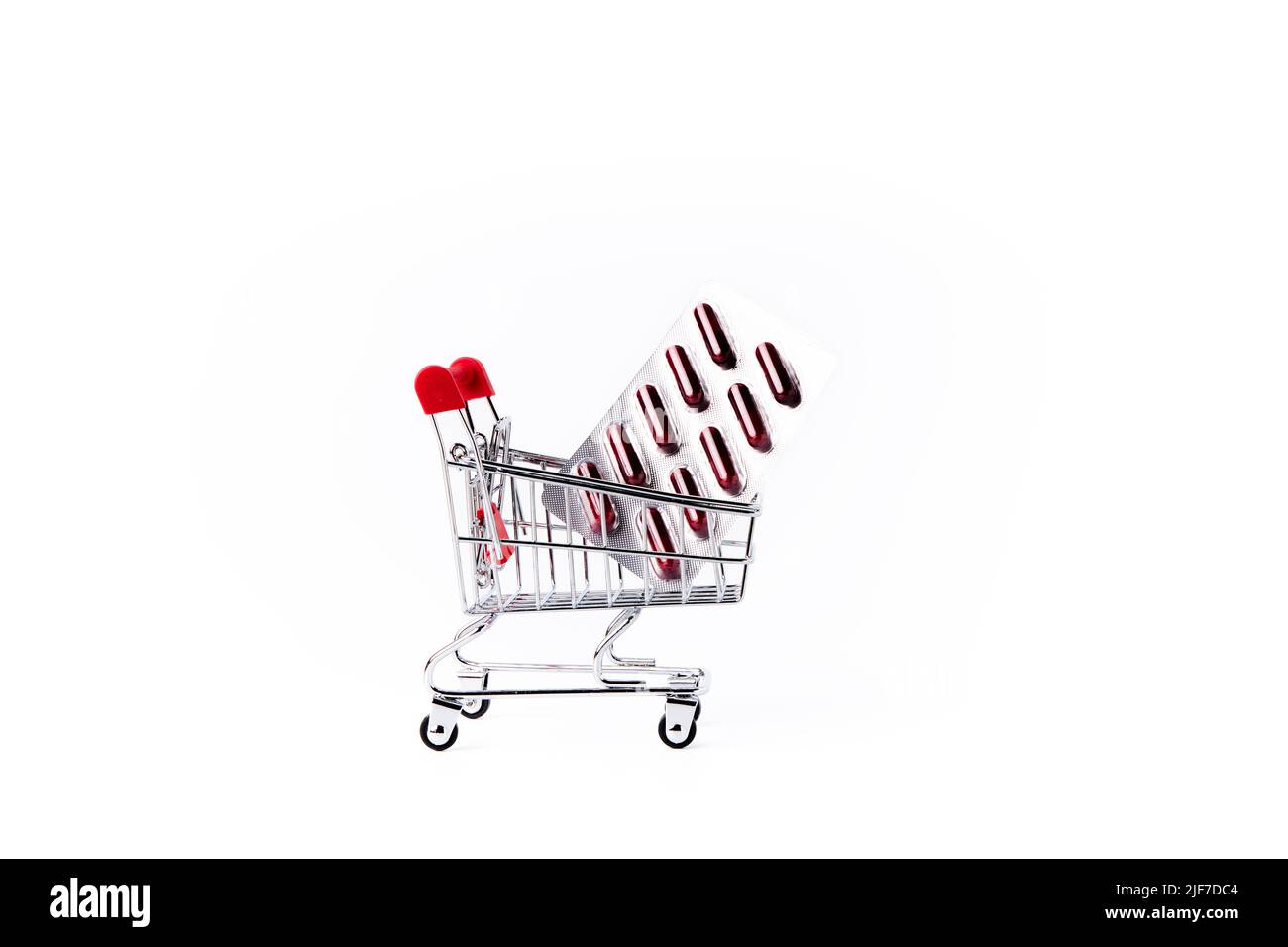 Shopping cart with a blister pack of medicines on a white background. Pharmacy and clinic concept Stock Photo