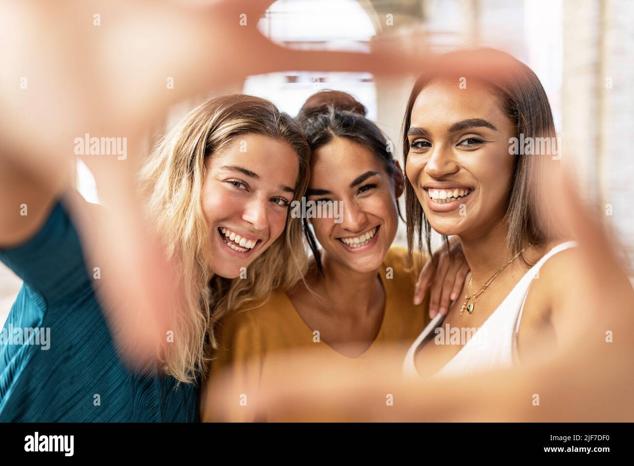 Three multiracial female friends making hand frame gesture in the street Stock Photo