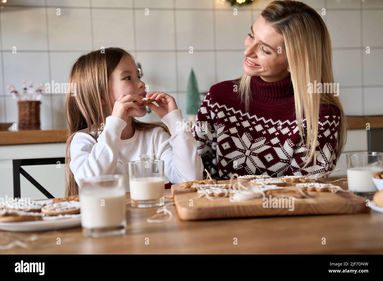 Happy mom and kid daughter having fun eating Christmas cookies. Stock Photo