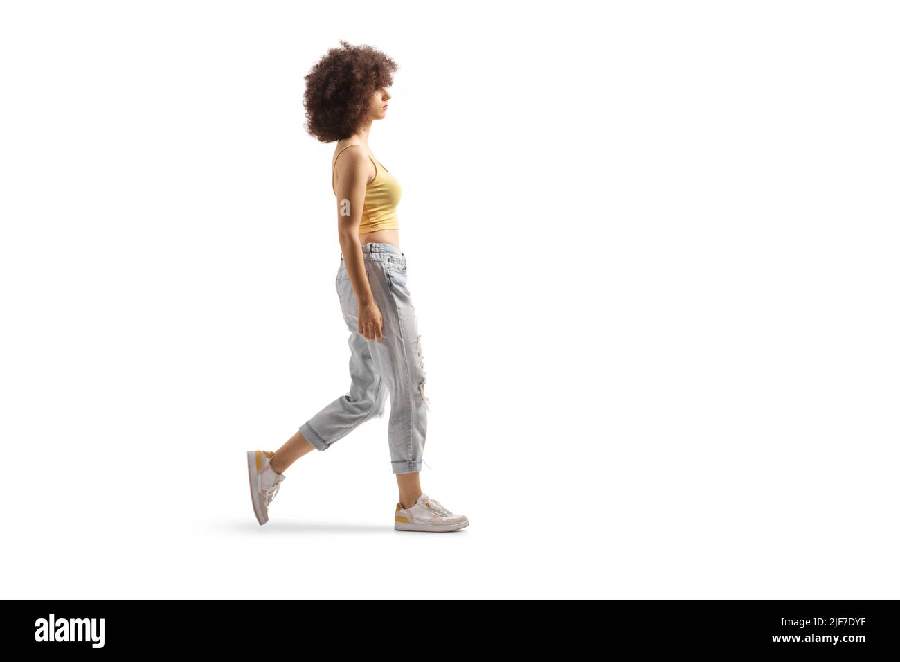 Full length profile shot of a young caucasian woman with afro hairstyle walking isolated on white background Stock Photo