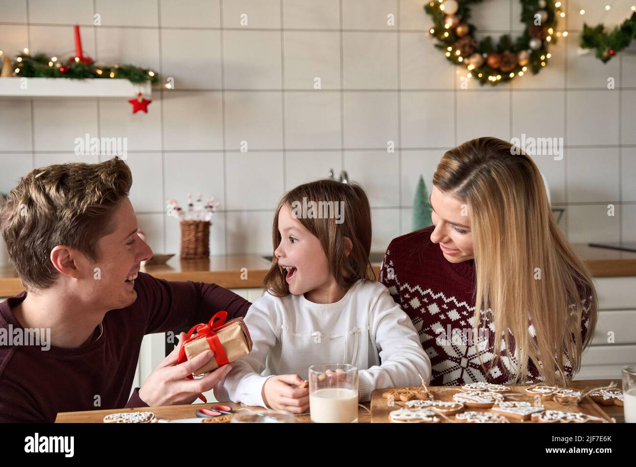 Dad presenting Christmas gift giving box to excited kid daughter at home. Stock Photo