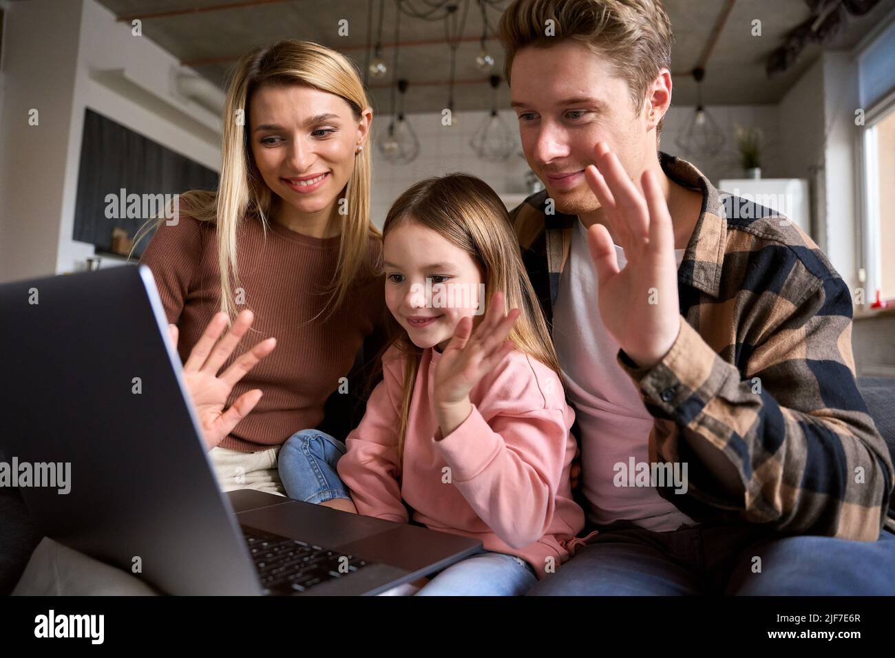 Happy parents and daughter having family video call using laptop at home. Stock Photo