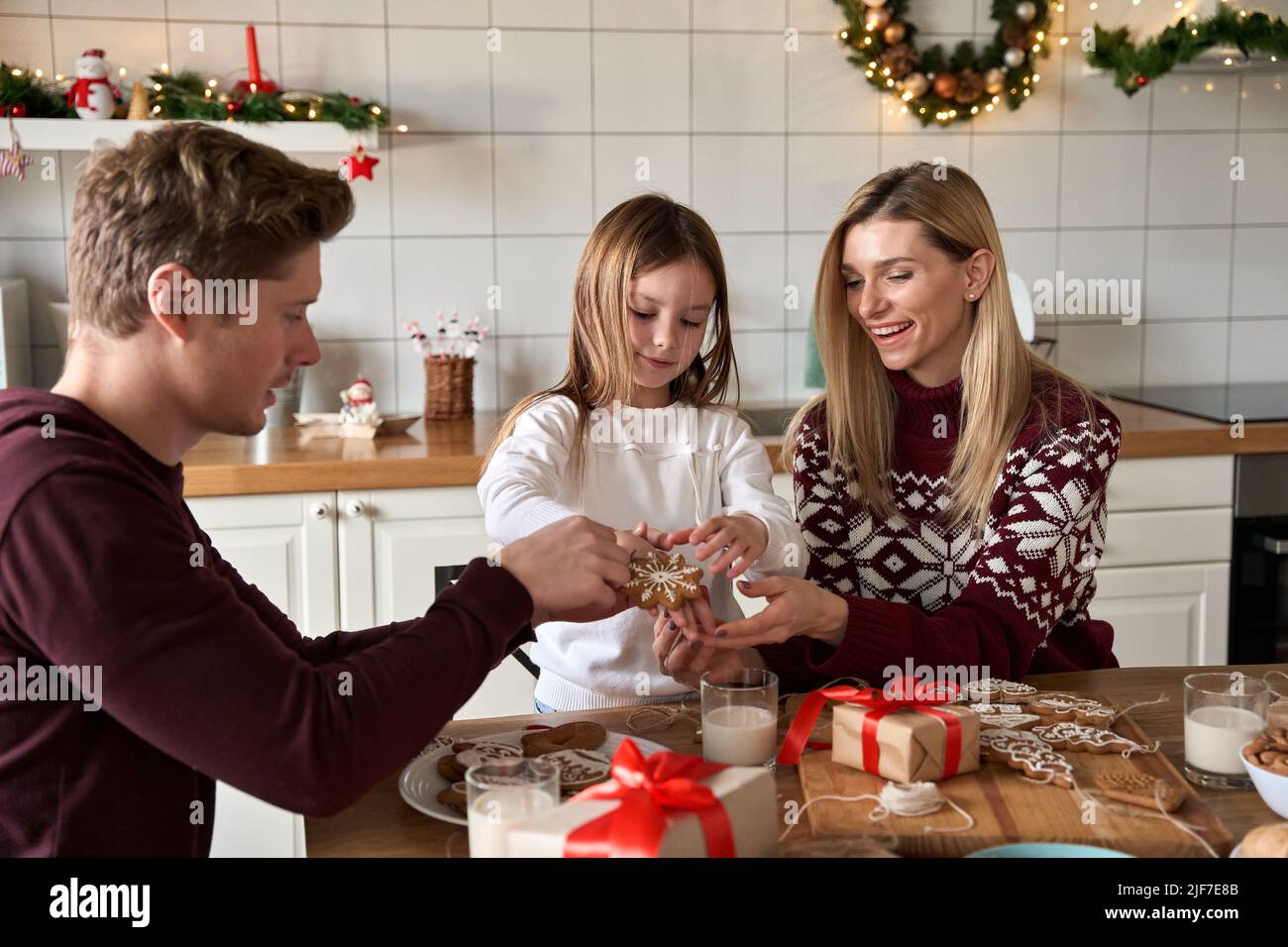 Happy parents and kid daughter having fun making Christmas cookies. Stock Photo