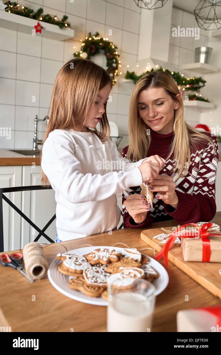 Mom helping cute small kid daughter making Christmas cookies Stock Photo