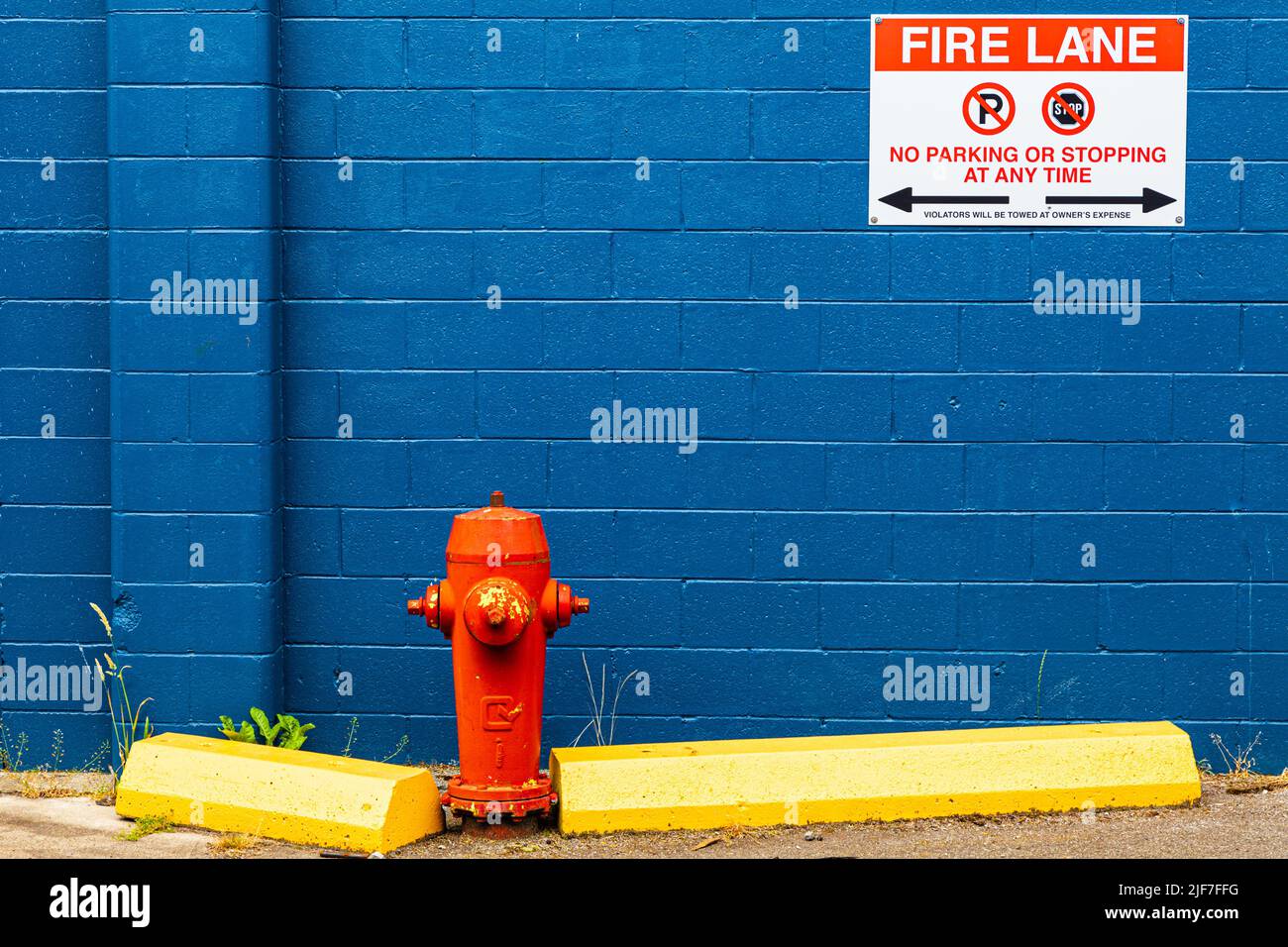 Blue painted wall with a red fire hydrant and yellow guard blocks at Steveston Harbour in British Columbia Canada Stock Photo