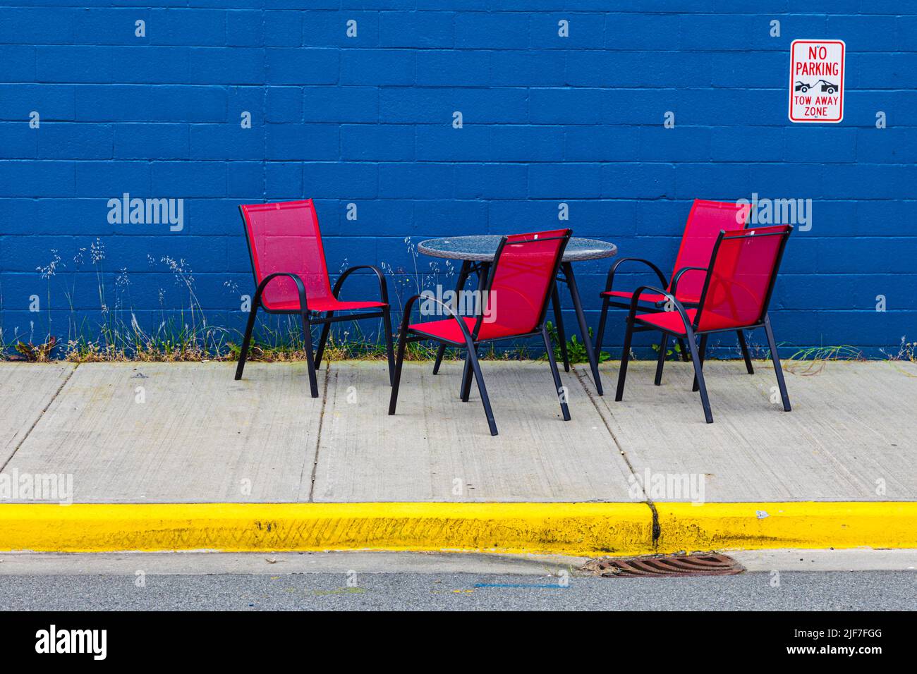 Table with red chairs against a blue wall in Steveston British Columbia Canada Stock Photo