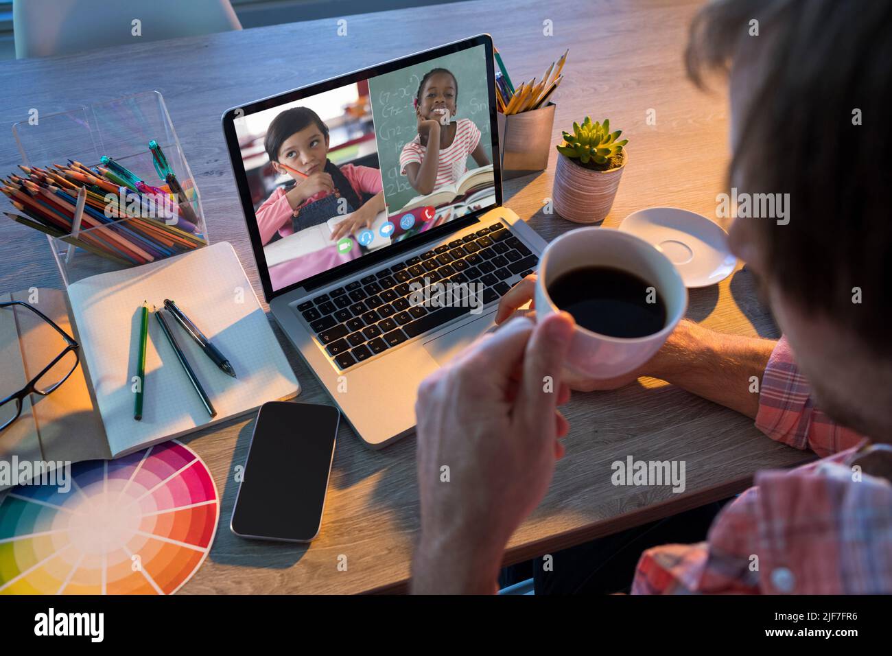 Caucasian male professor drinking coffee while teaching students online over video call at home Stock Photo