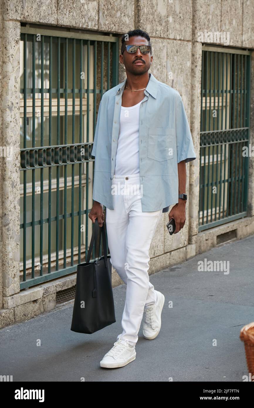 MILAN, ITALY - JUNE 20, 2022: Man with pale blue shirt, white trousers and sneakers before Giorgio Armani fashion show, Milan Fashion Week street styl Stock Photo