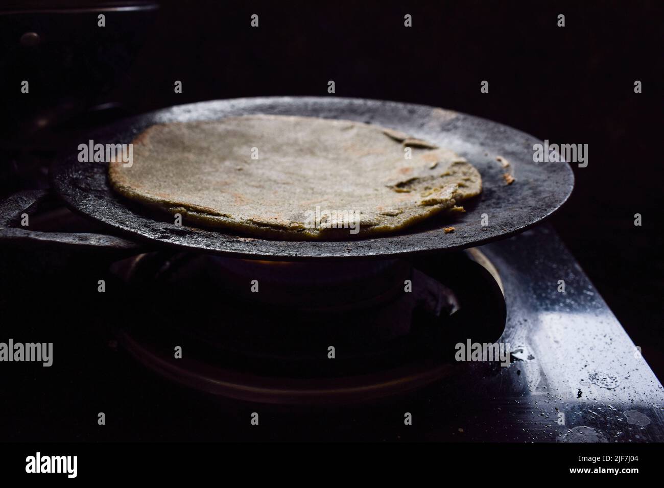 flatbread made of pearl millet known as Bajre ki roti. Dough is flattened with hands to make round circle. Village style chulha prepared in farm or ki Stock Photo