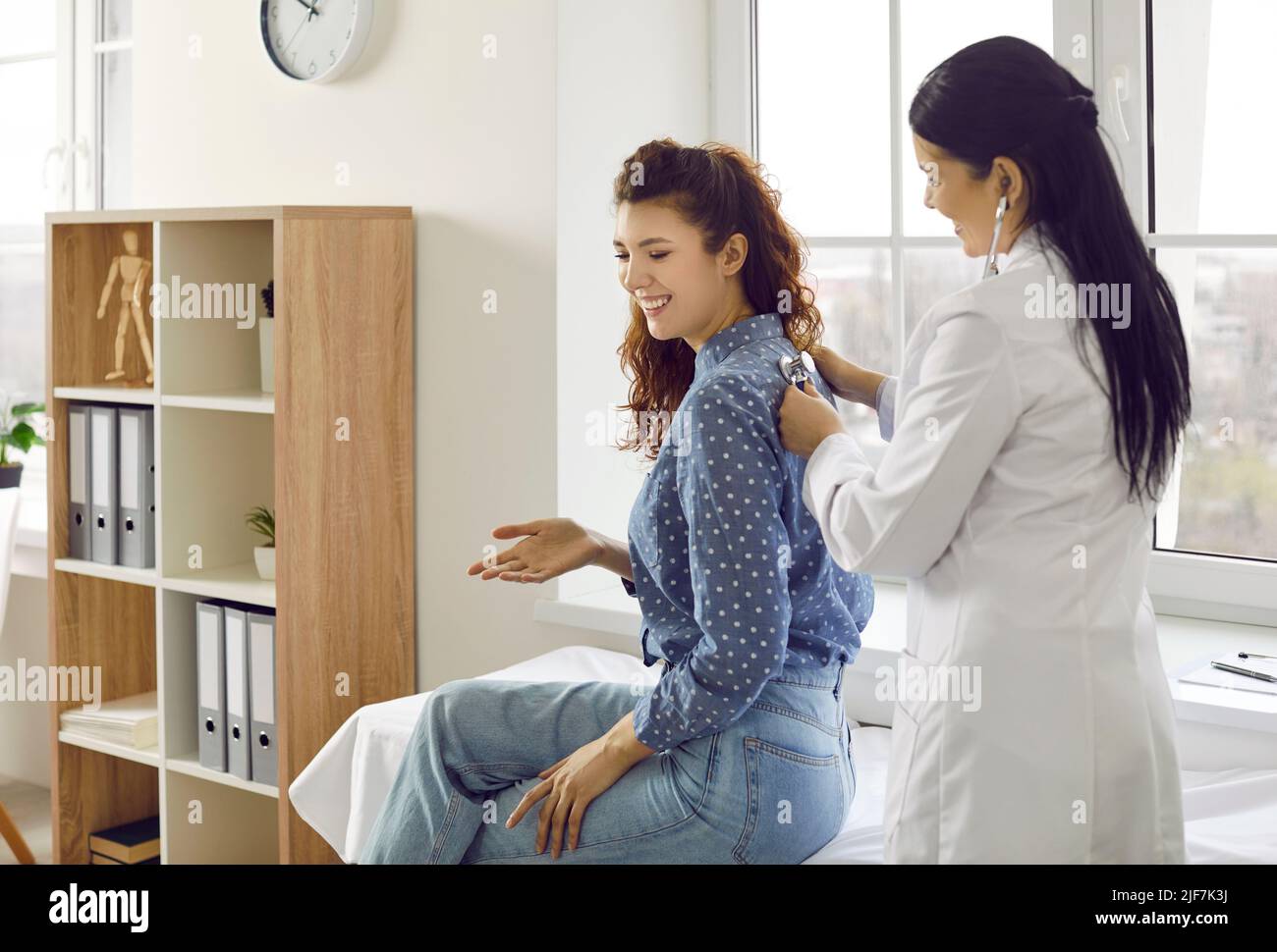 Nurse listens to female patient's back to check her lungs, breathing or ...