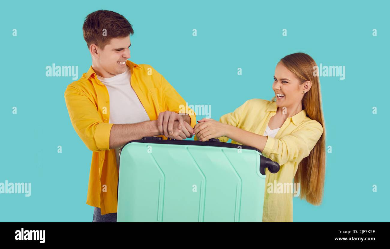 Funny young couple who are going on holiday trip together are fighting for suitcase Stock Photo