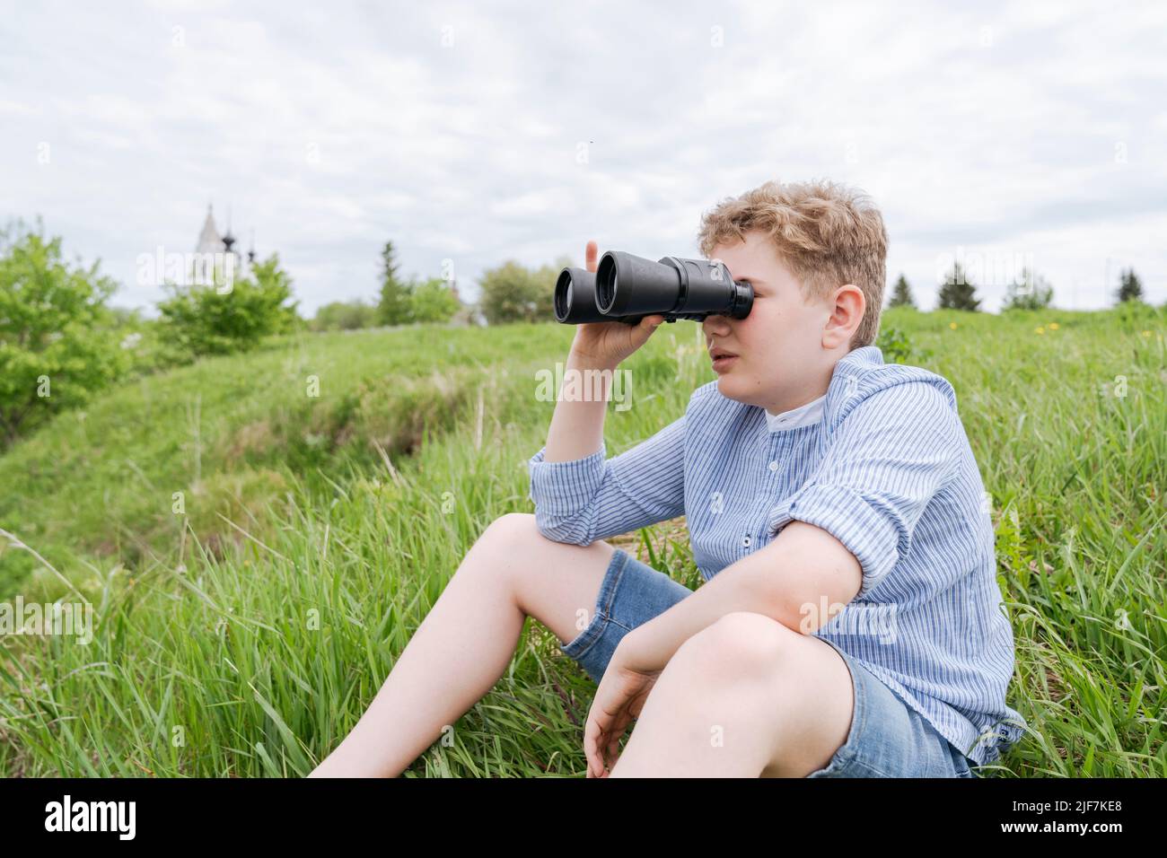 An 11-year-old boy on a walk, look through binoculars. Stock Photo