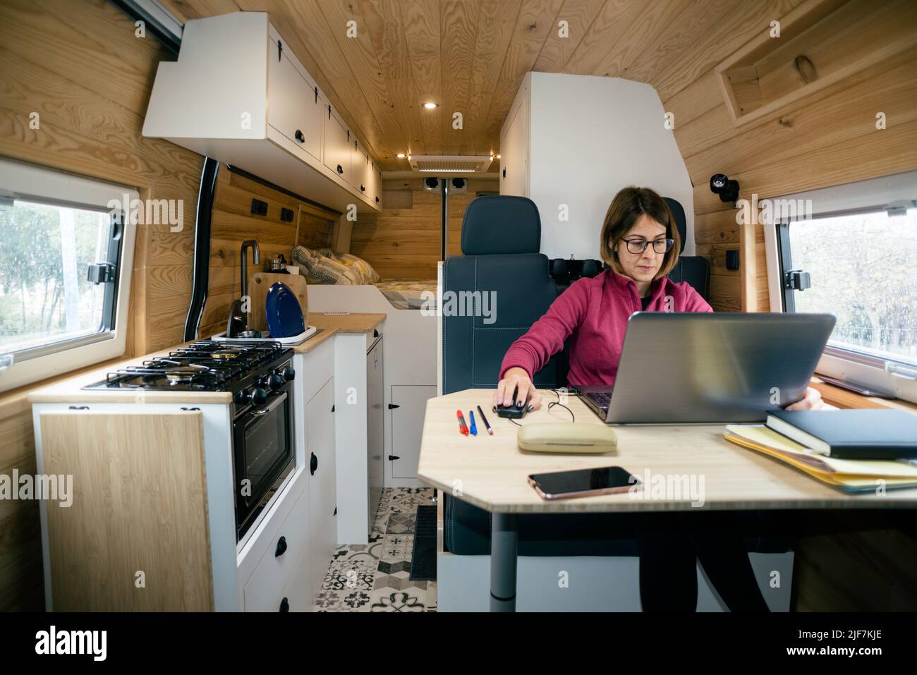 Vanlife. Woman doing remote work with the computer in the motorhome. Stock Photo