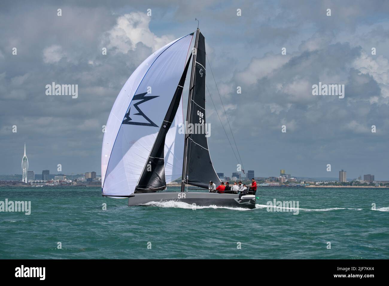 GBR5R Sailing Yacht Gelert with its spinnaker sail inflated, passes the Spinnaker tower in Portsmouth as it sails up the Solent to take a 4th Place Stock Photo