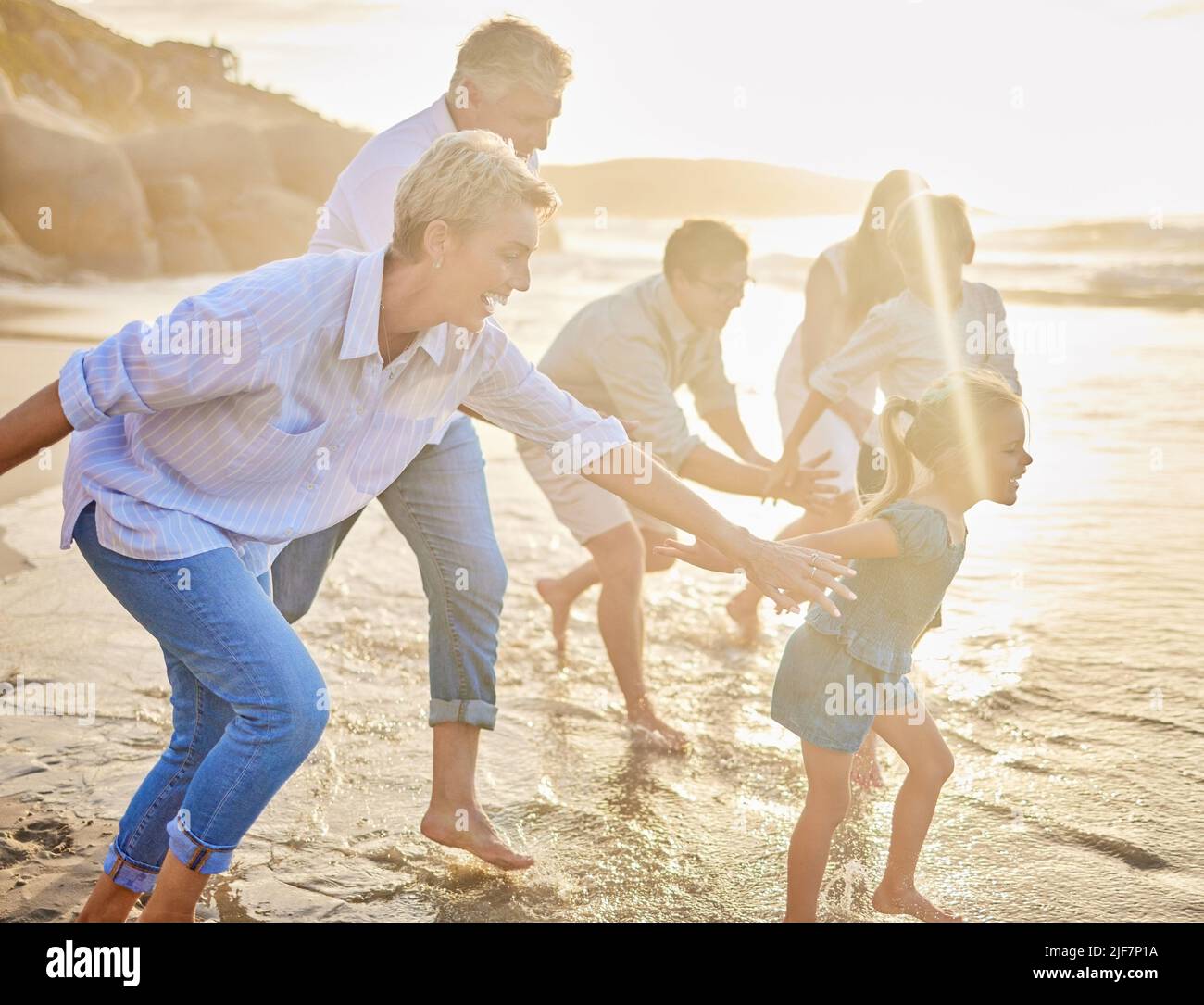 Multi generation family holding hands and walking along the beach together. Caucasian family with two children, two parents and grandparents enjoying Stock Photo