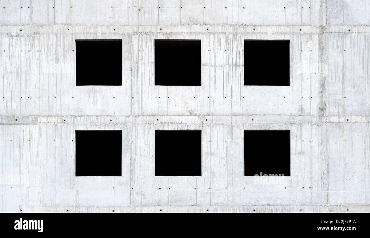 Six empty square windows, black window holes on a grey raw concrete wall, unfinished building side view, detail, frontal, front view, nobody. Building Stock Photo