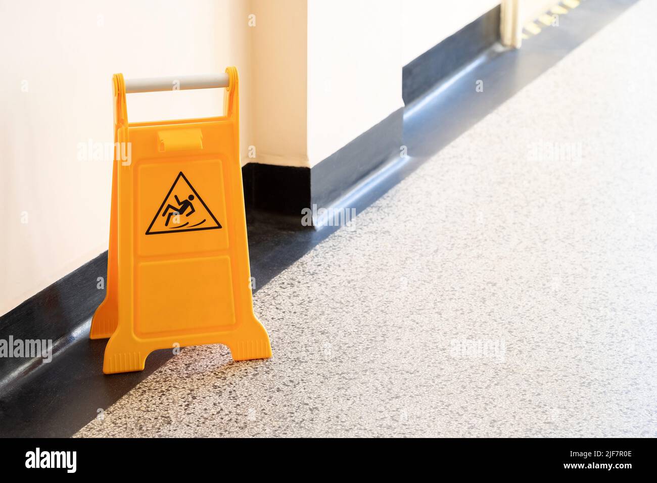 Caution wet floor orange fold out sign without text in a bright ...