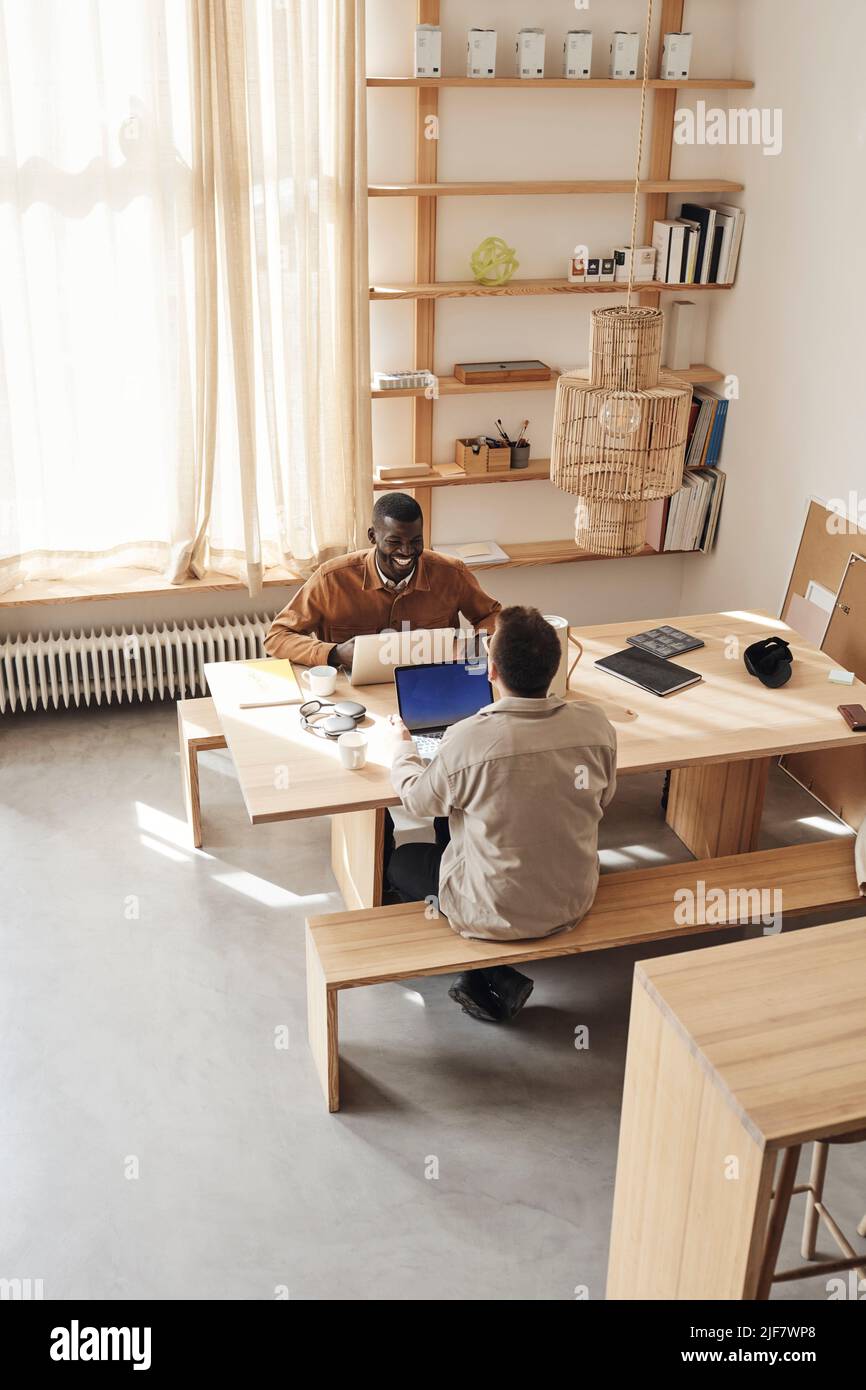 Male programmers discussing while sitting at desk in tech start-up office Stock Photo
