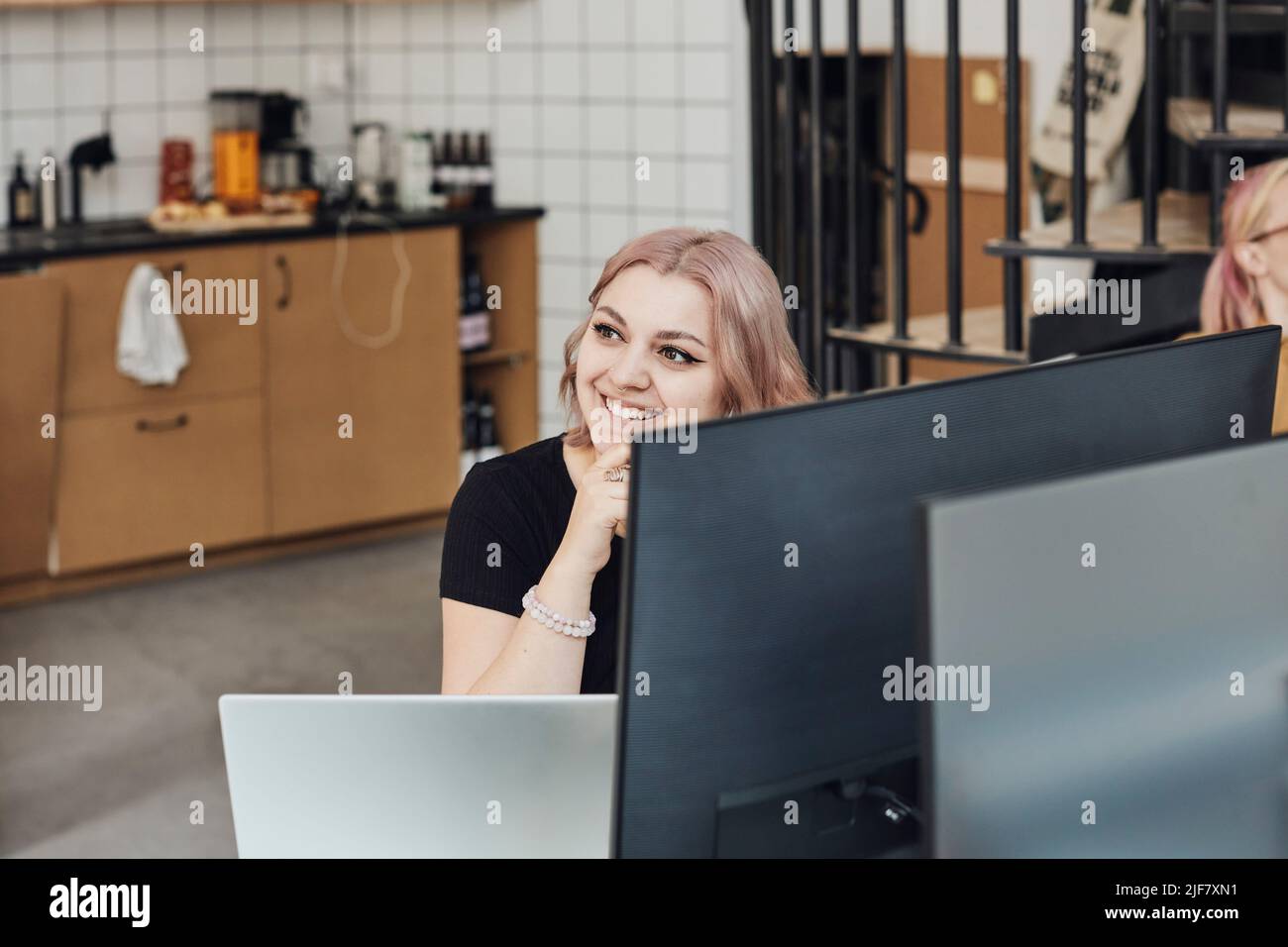 Female entrepreneur smiling during meeting in tech start-up office Stock Photo