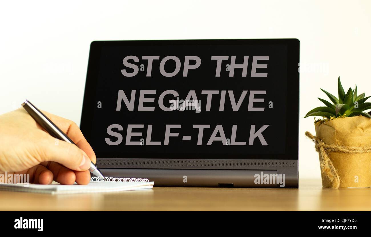 Stop negative self-talk symbol. Concept words Stop the negative self-talk on the black tablet. Businessman hand with pen. Psychological and stop negat Stock Photo