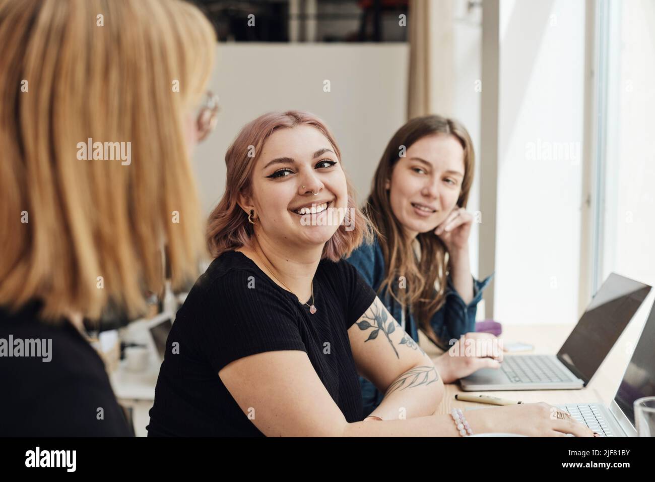 Smiling female entrepreneurs looking at colleague during meeting in office Stock Photo