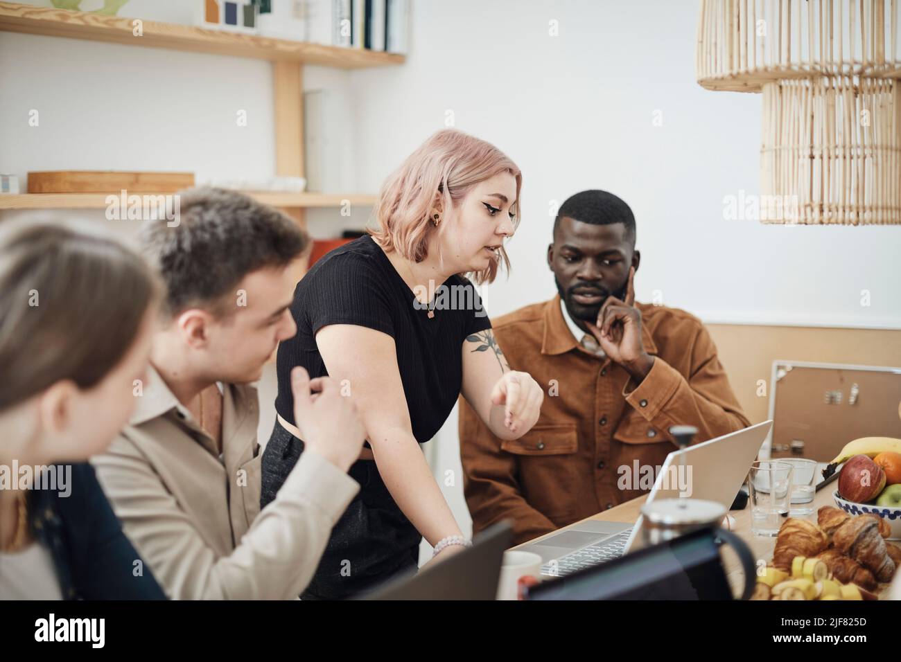 Female computer programmer explaining colleagues at tech start-up office Stock Photo