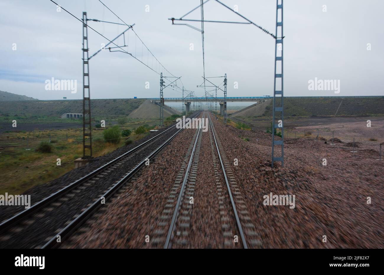 electric train lines with overhead power lines and a grey sky Stock Photo