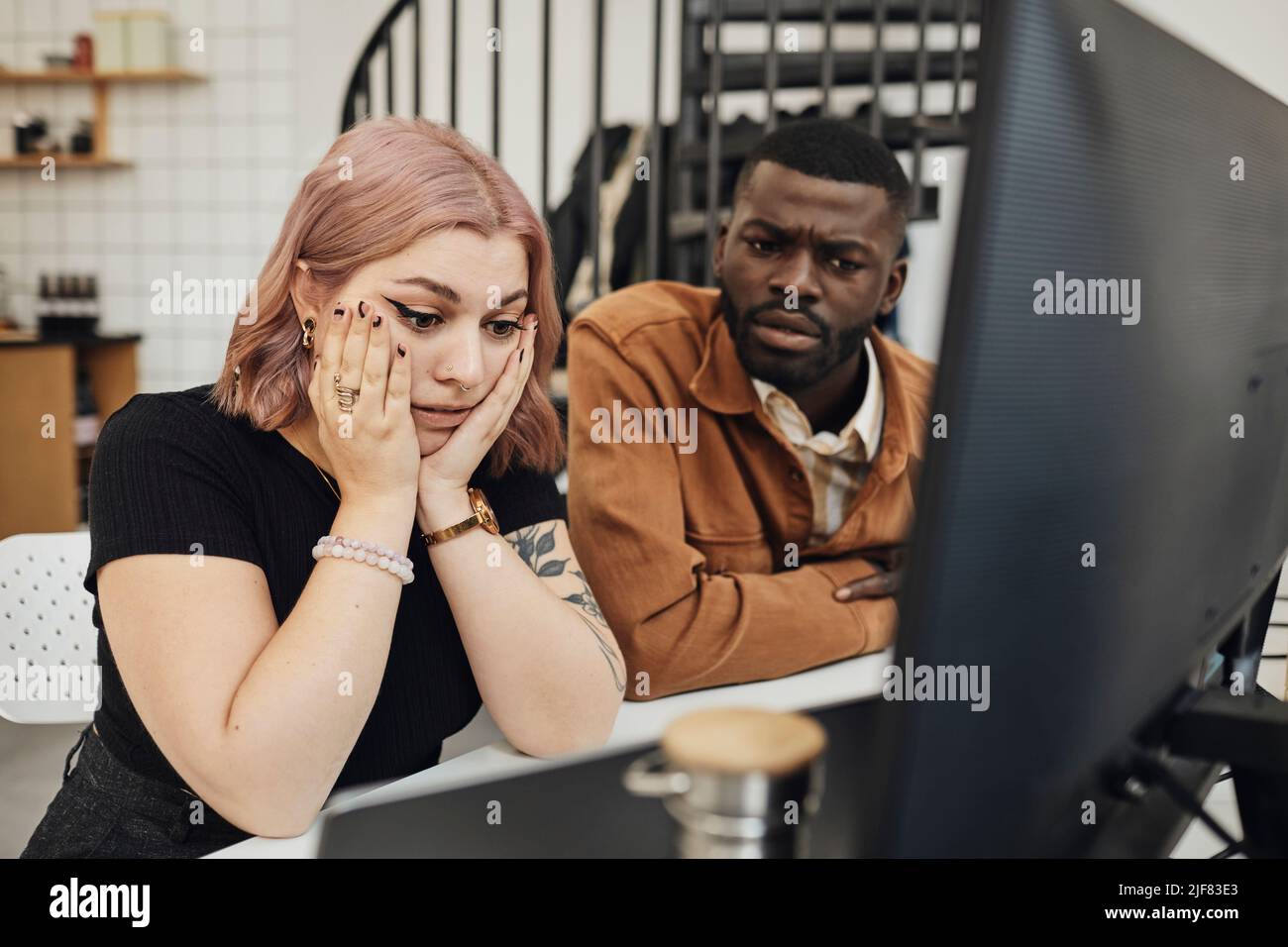 Worried businesswoman and businessman looking at computer monitor in office Stock Photo