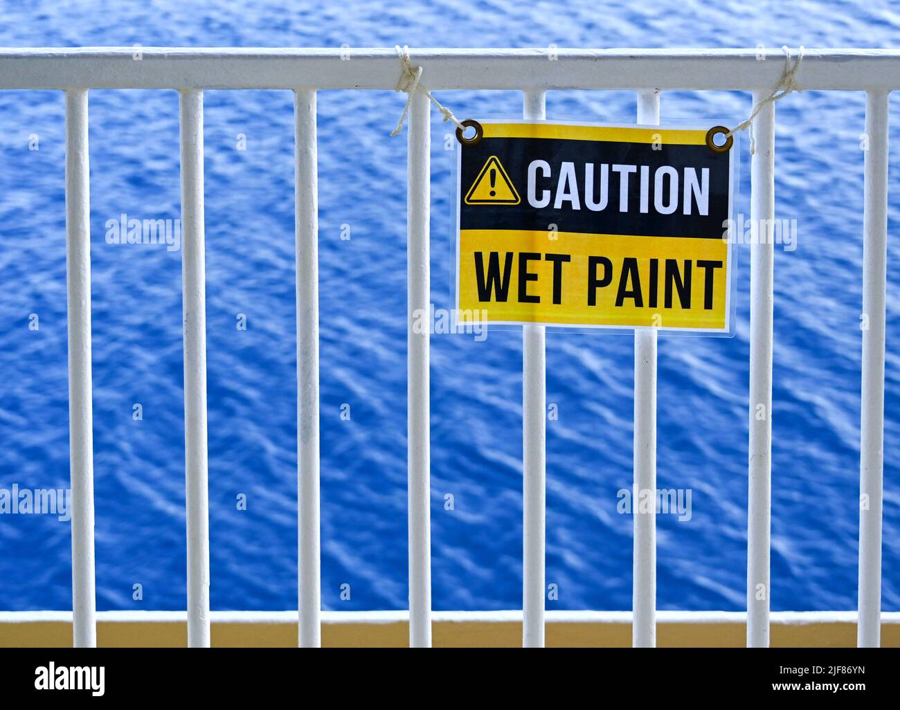wet-paint-sign-on-metal-railings-with-the-sea-in-the-background-no
