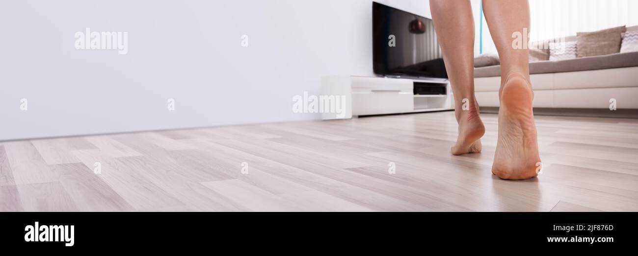 Low Section View Of An Foot Walking On Heated Hardwood Floor Stock