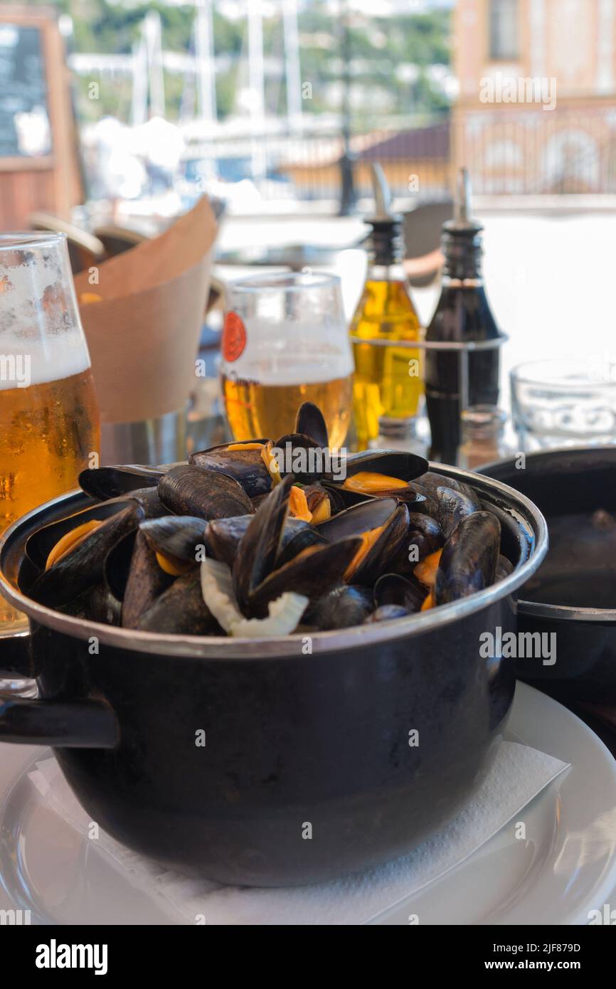 Cooked mussels in a black bowl and beer in a restaurant. Seafood